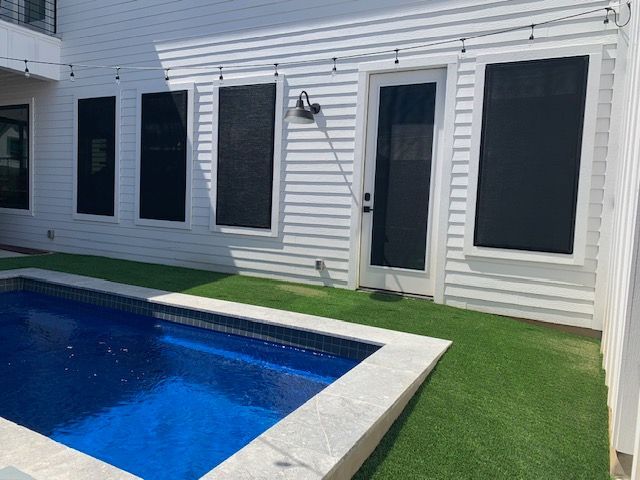 There is a swimming pool in the backyard of a house.