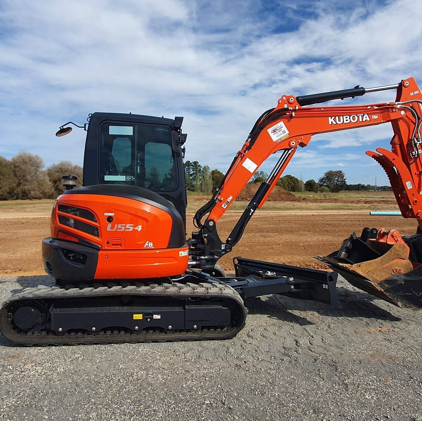 A Small Orange Excavator Is Parked On The Side Of The Road — Grants Excavations In Osbornes Flat, VIC