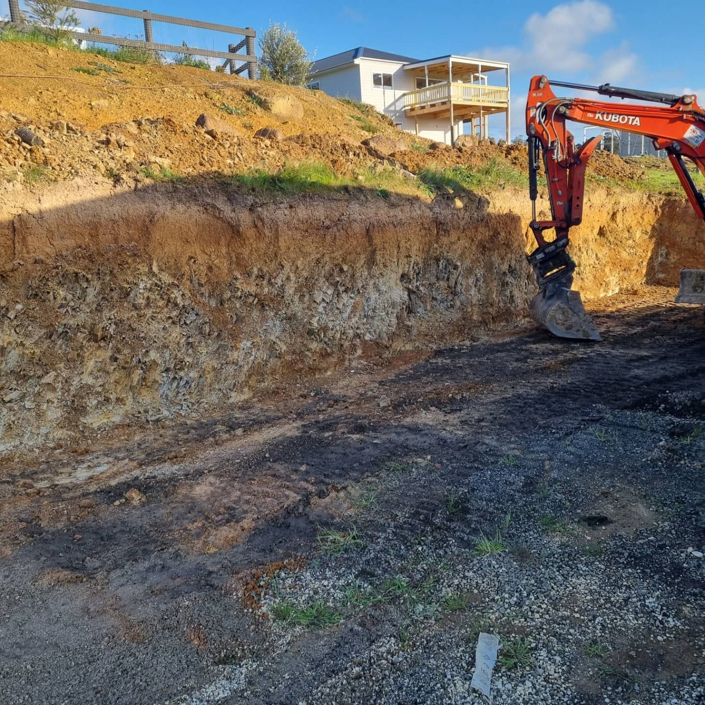 A Large Excavator Is Digging A Hole In The Dirt In Front Of A House — Grants Excavations In Osbornes Flat, VIC