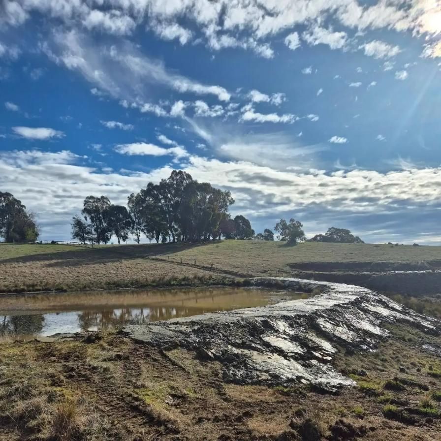 A Body Of Water With Trees In The Background And A Blue Sky With Clouds — Grants Excavations In Osbornes Flat, VIC