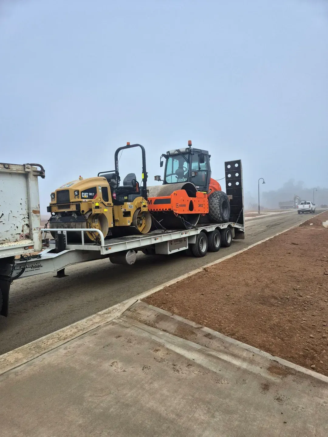 A Truck Is Carrying A Tractor And A Roller On A Trailer — Grants Excavations In Osbornes Flat, VIC