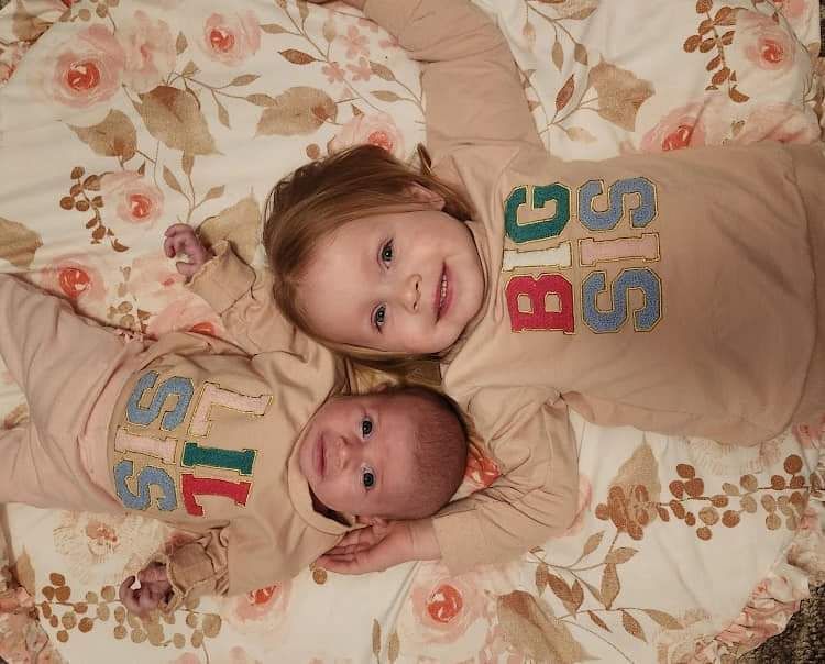 Toddler and baby lying head to head in a crib