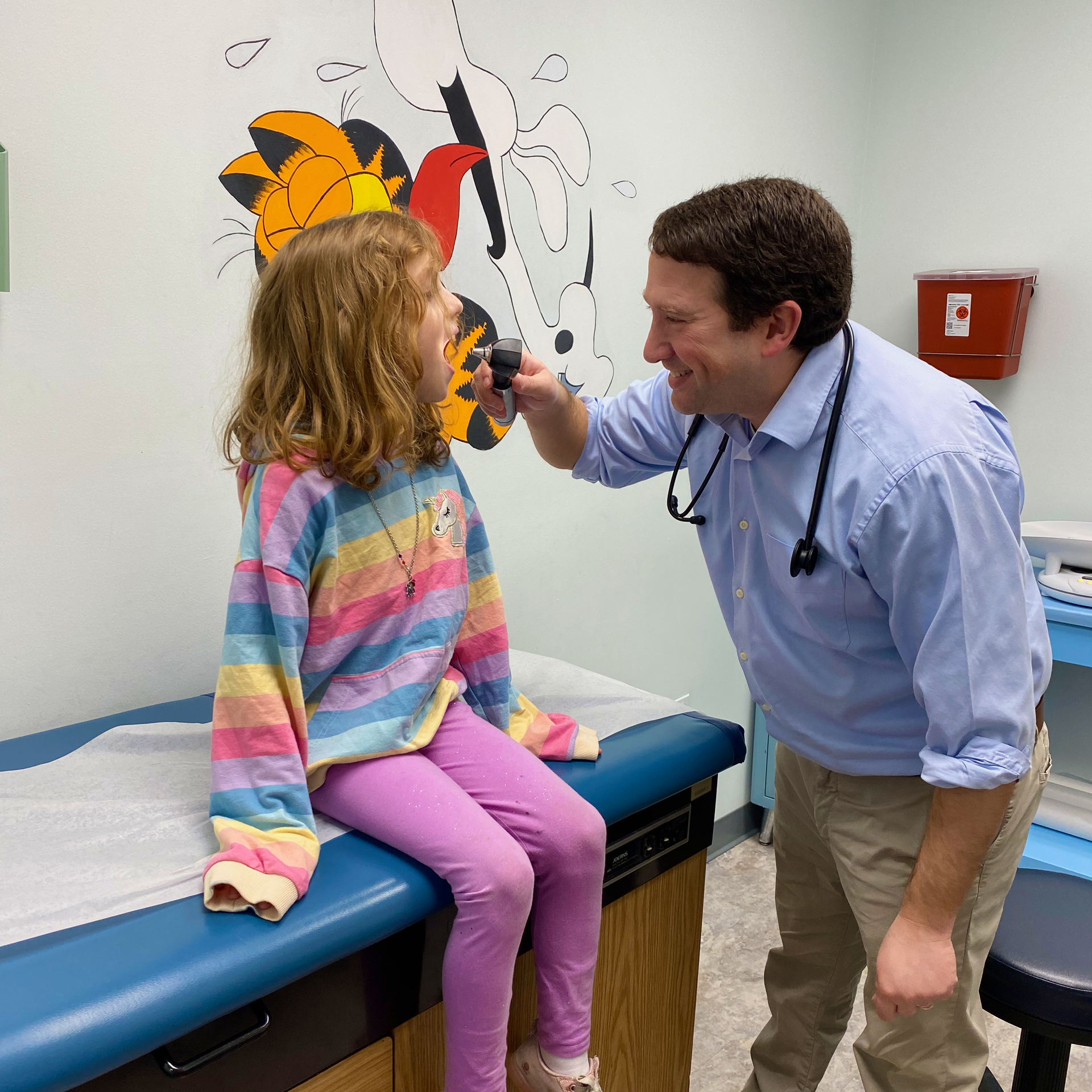 A doctor examines a little girl 's ear with a medical device