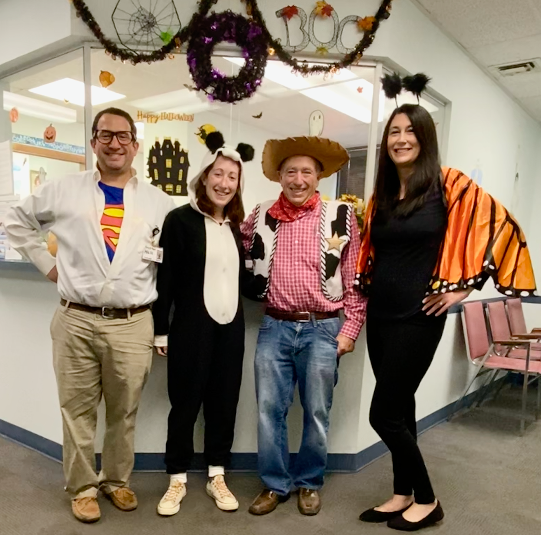 A group of people are posing for a picture in front of a window that says happy halloween.