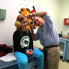 A girl wearing headphones is being examined by a doctor