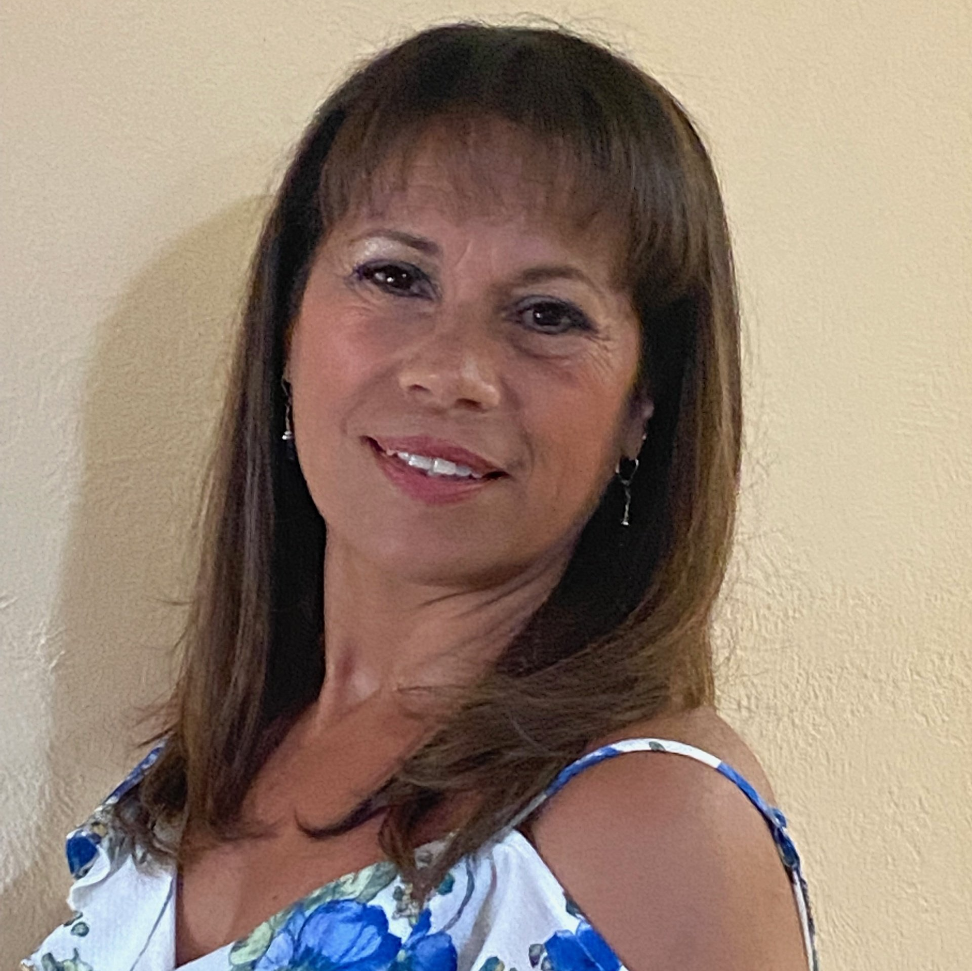 A woman in a blue and white floral dress is smiling for the camera.