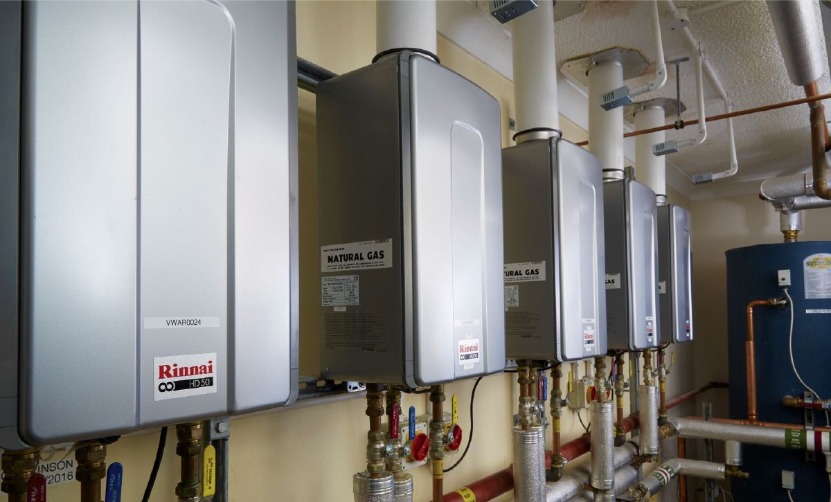 A row of water heaters are lined up on a wall.