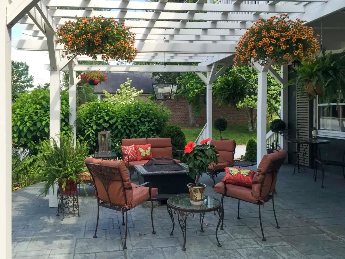 a patio with a fire pit and chairs under a pergola