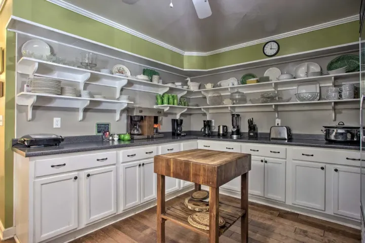 a kitchen with white cabinets and a wooden island with a cutting board on it .