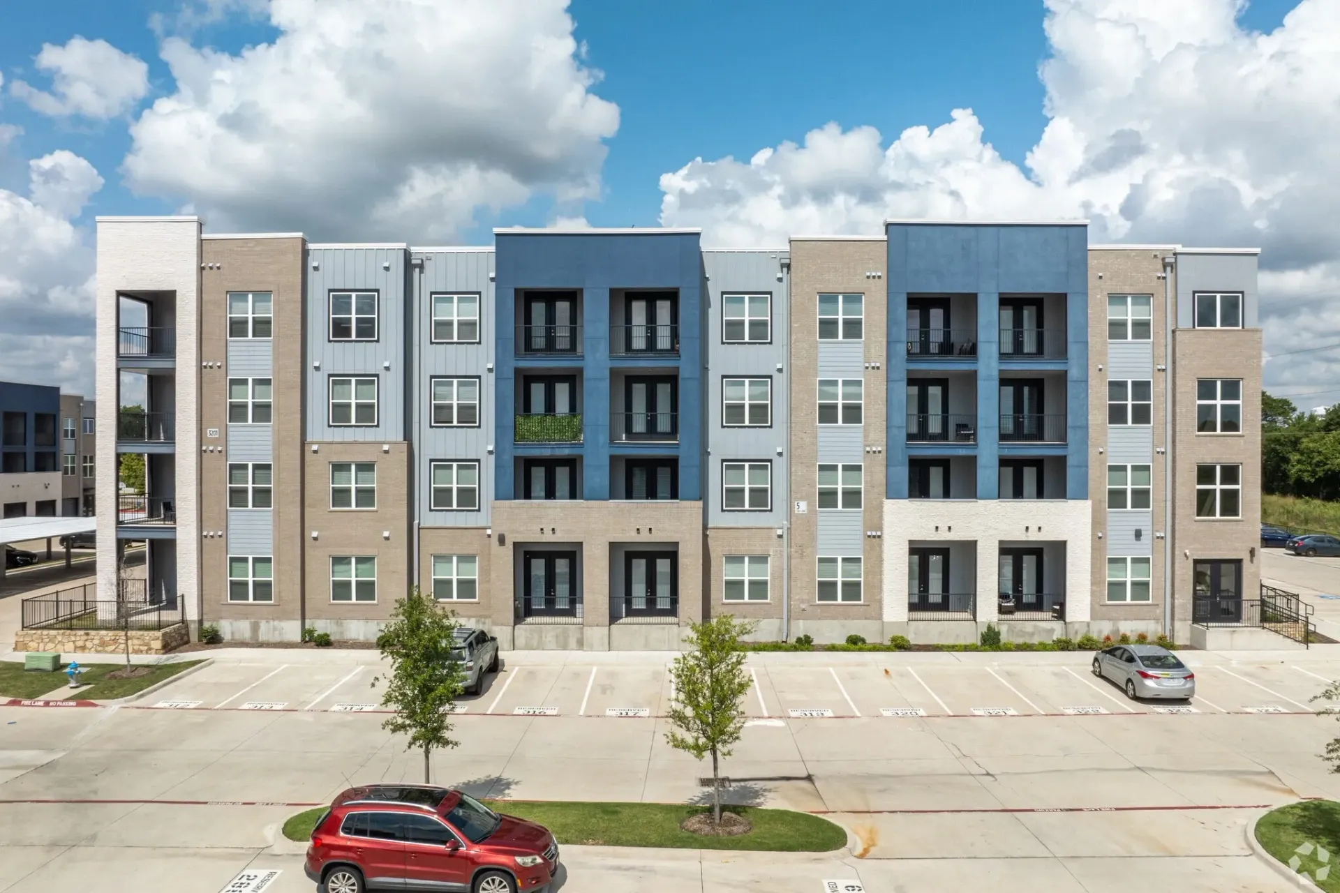 Exterior view of a modern apartment building with balconies and parking.