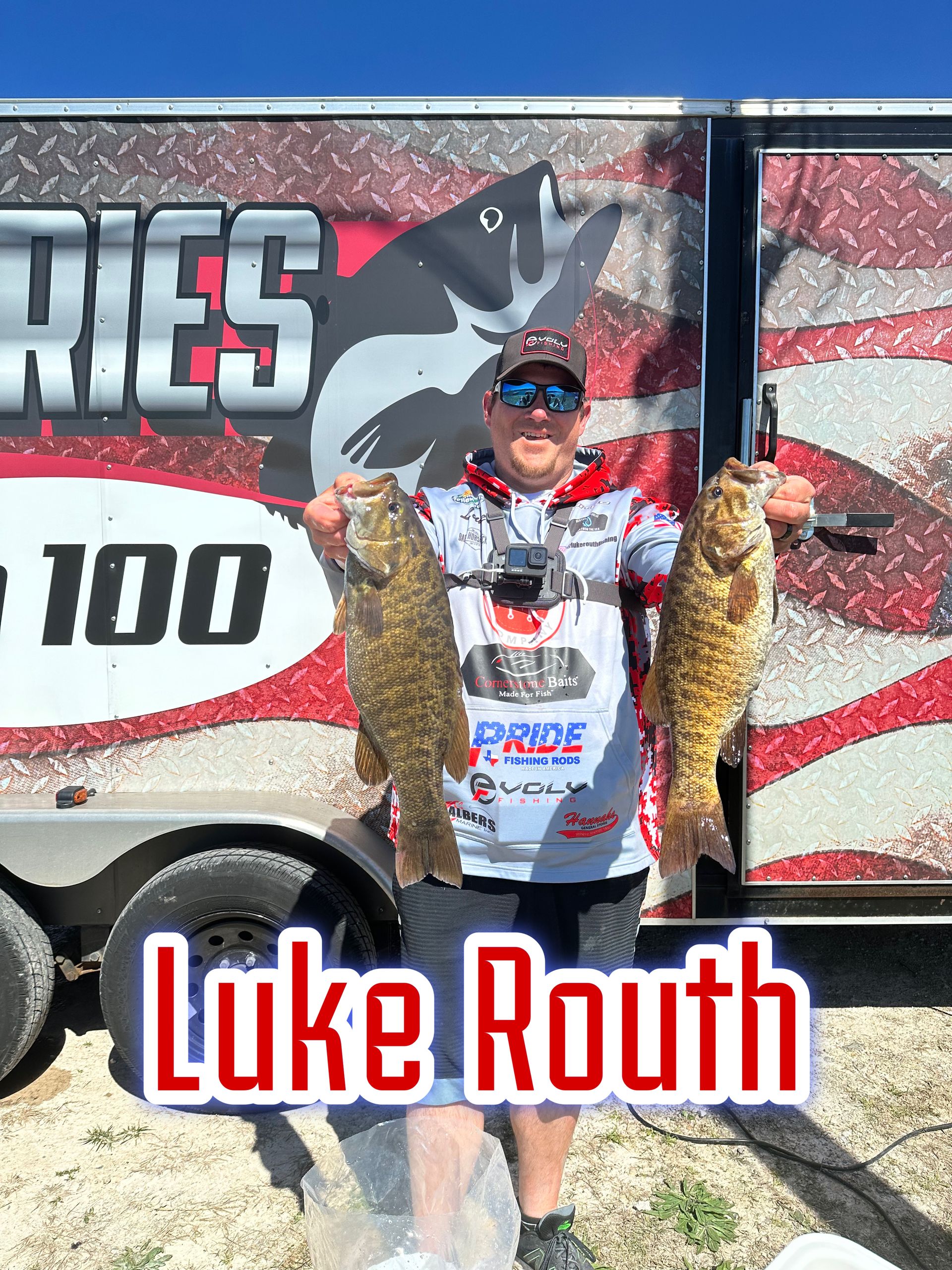 Man holding two fish in front of a fishing trailer with “Luke Routh” text overlay.