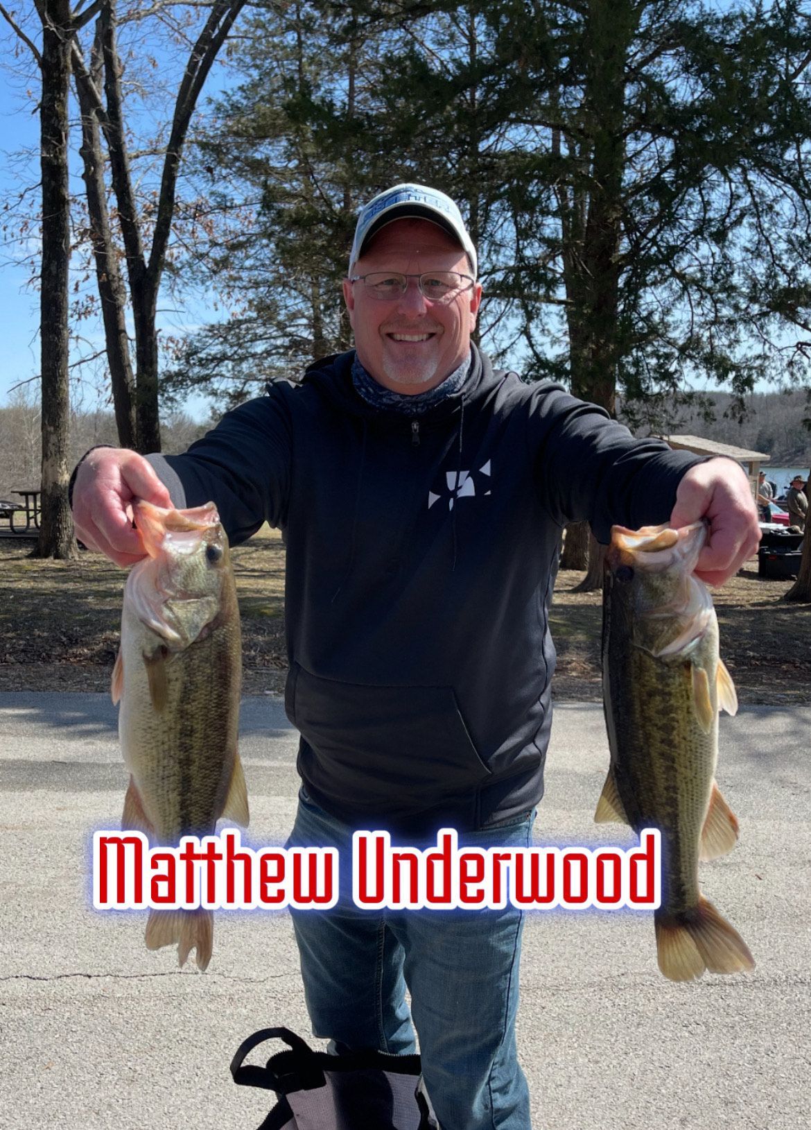 Man holding two fish outdoors with trees in the background; text reads “Matthew Underwood”