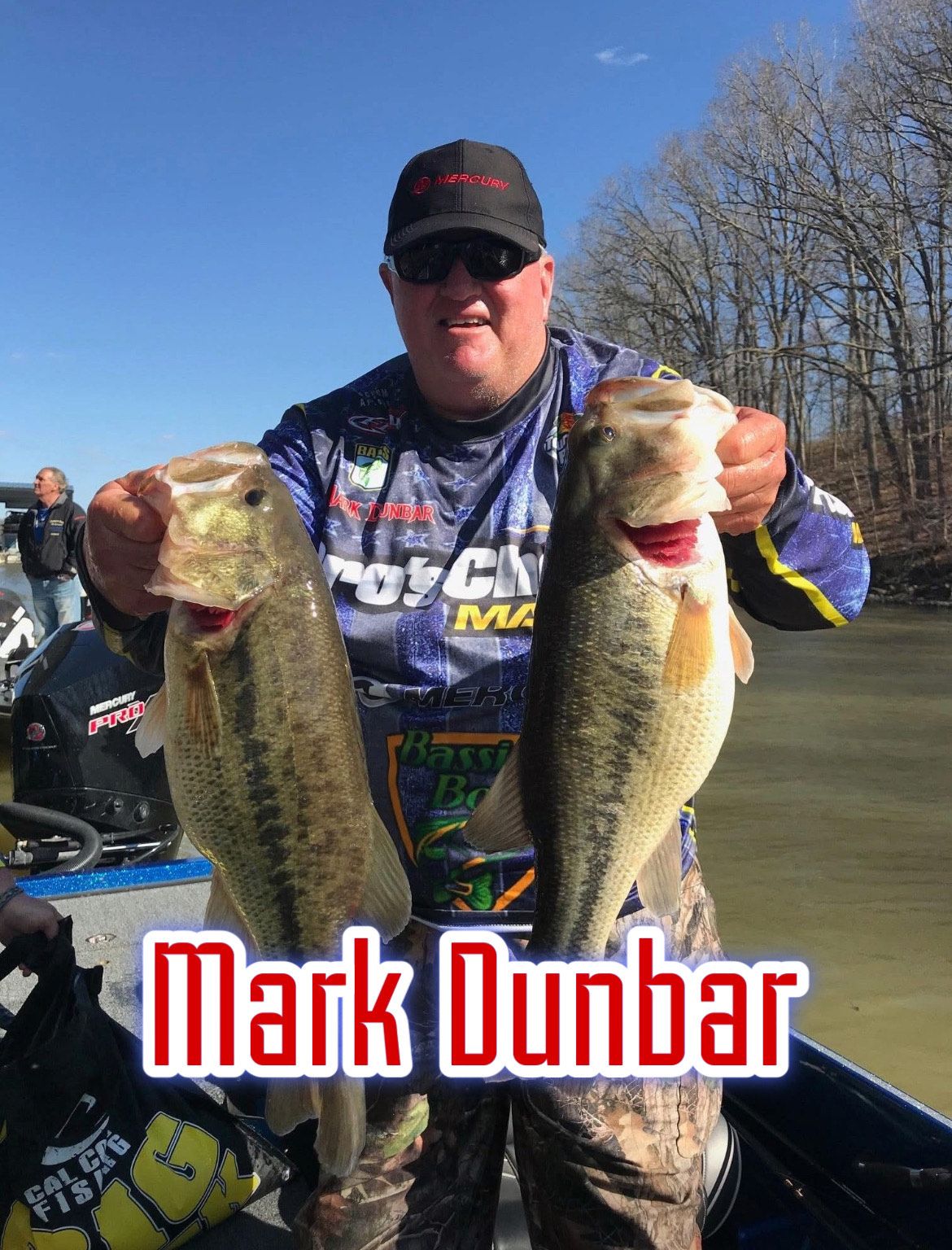Man holding two large bass on a boat, with “Mark Dunbar” text at the bottom.