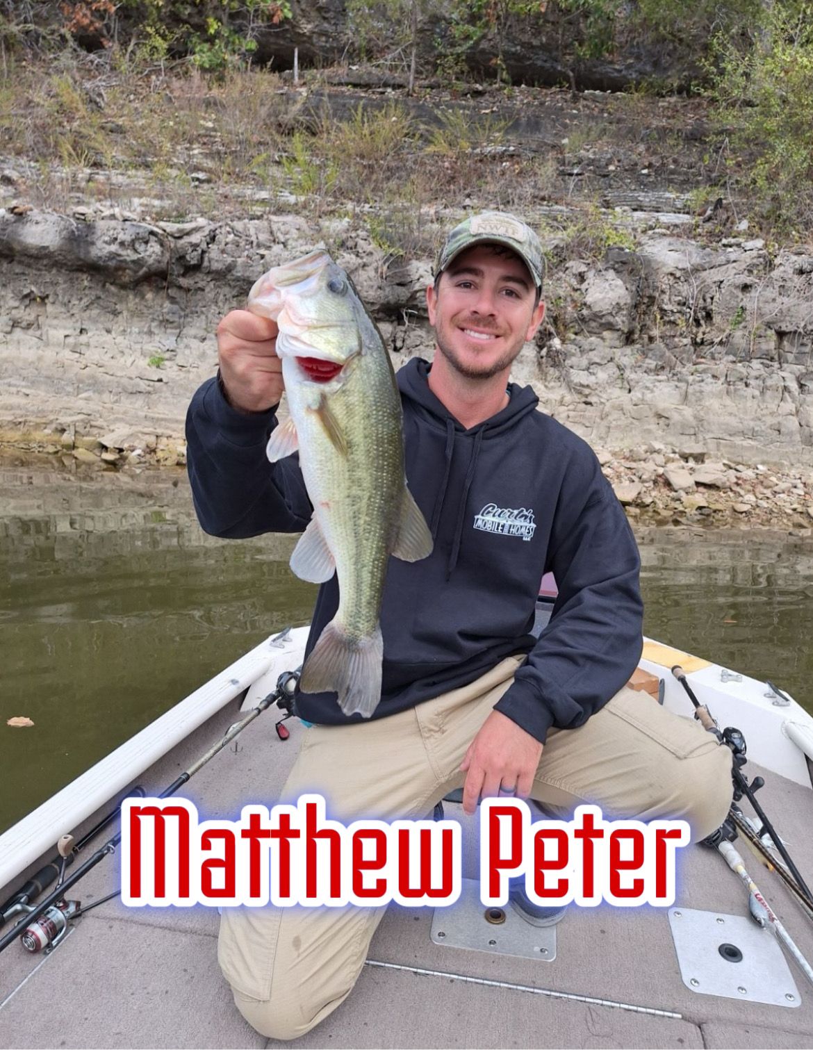 Man sitting in a boat holding a large bass fish, with “Matthew Peter” text at the bottom.