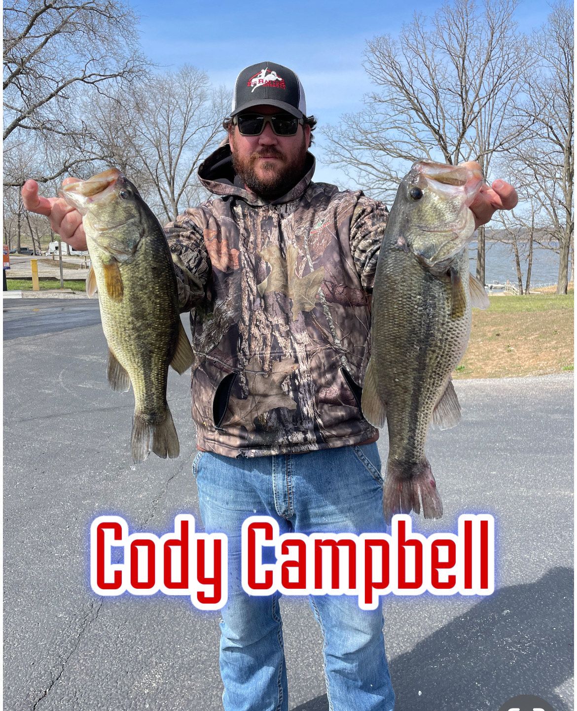 Man in camo holding two large bass outdoors, with “Cody Campbell” text at the bottom.