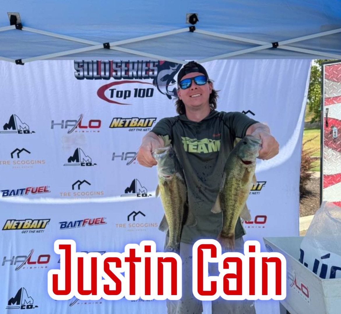 Angler holding two largemouth bass under a tournament canopy, with “Justin Cain” text overlay