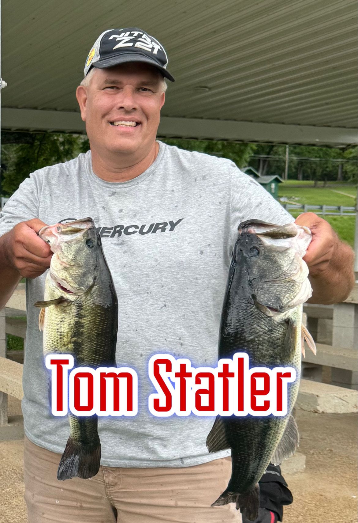 Man smiling under a canopy, holding two large fish, with “Tom Statler” text across the bottom.