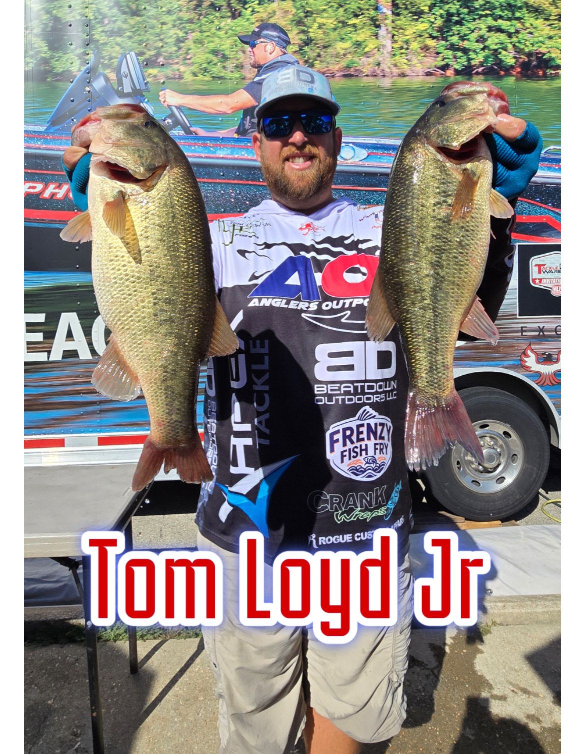 Angler holding two large bass in front of a tournament boat, labeled “Tom Loyd Jr.”
