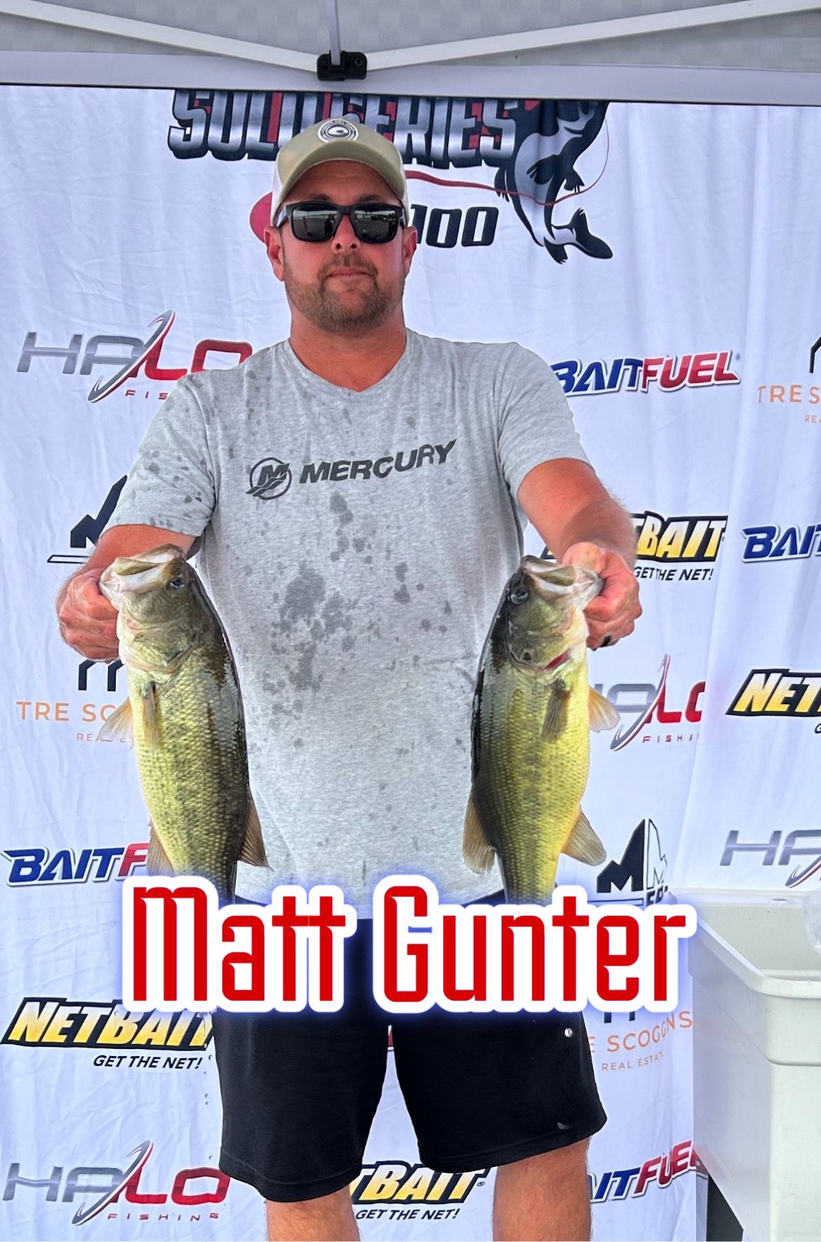 Man holding two large fish at a fishing event banner, with name text “Matt Gunter” at bottom.
