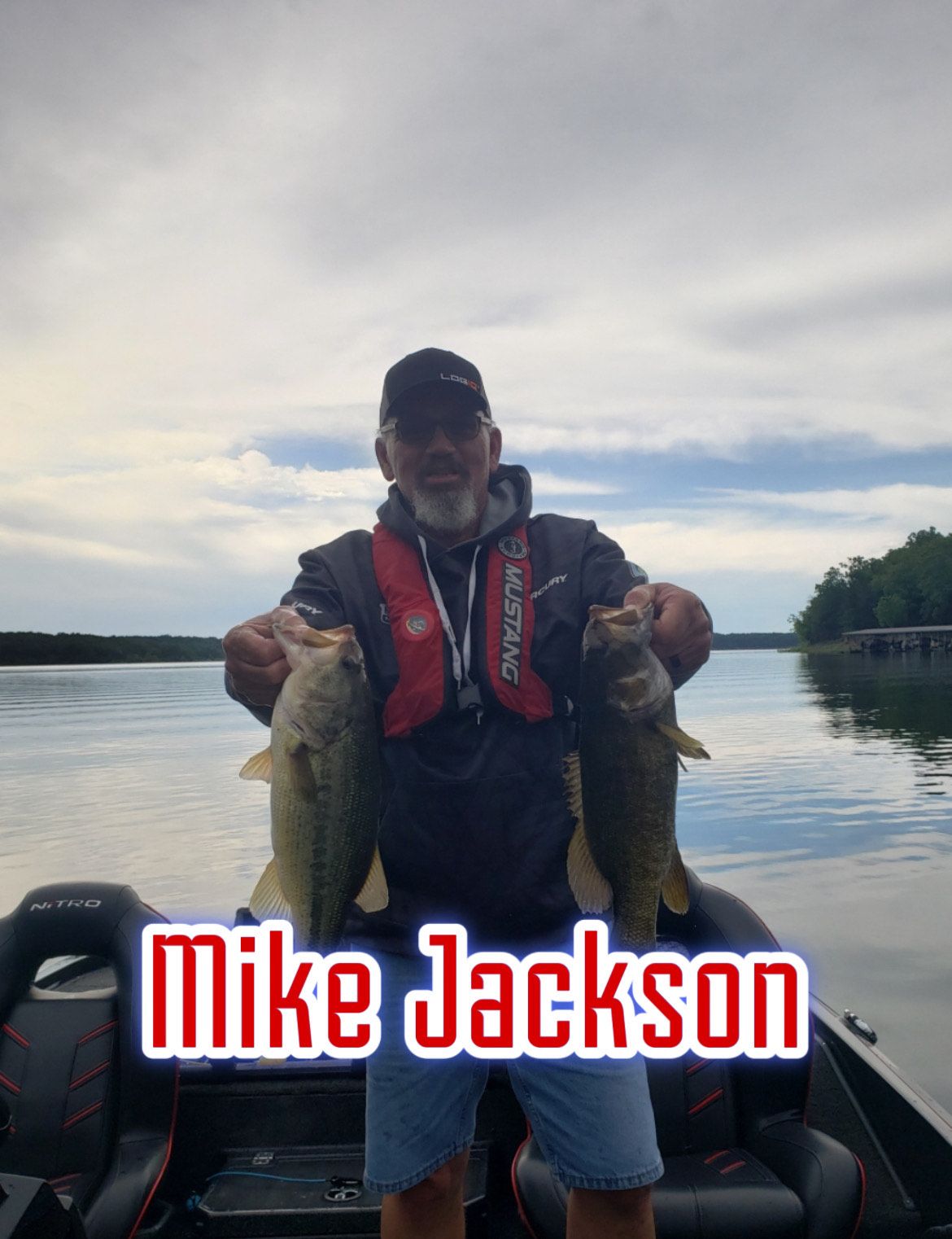Man on a boat holding two large fish, with “Mike Jackson” text overlaid at the bottom.