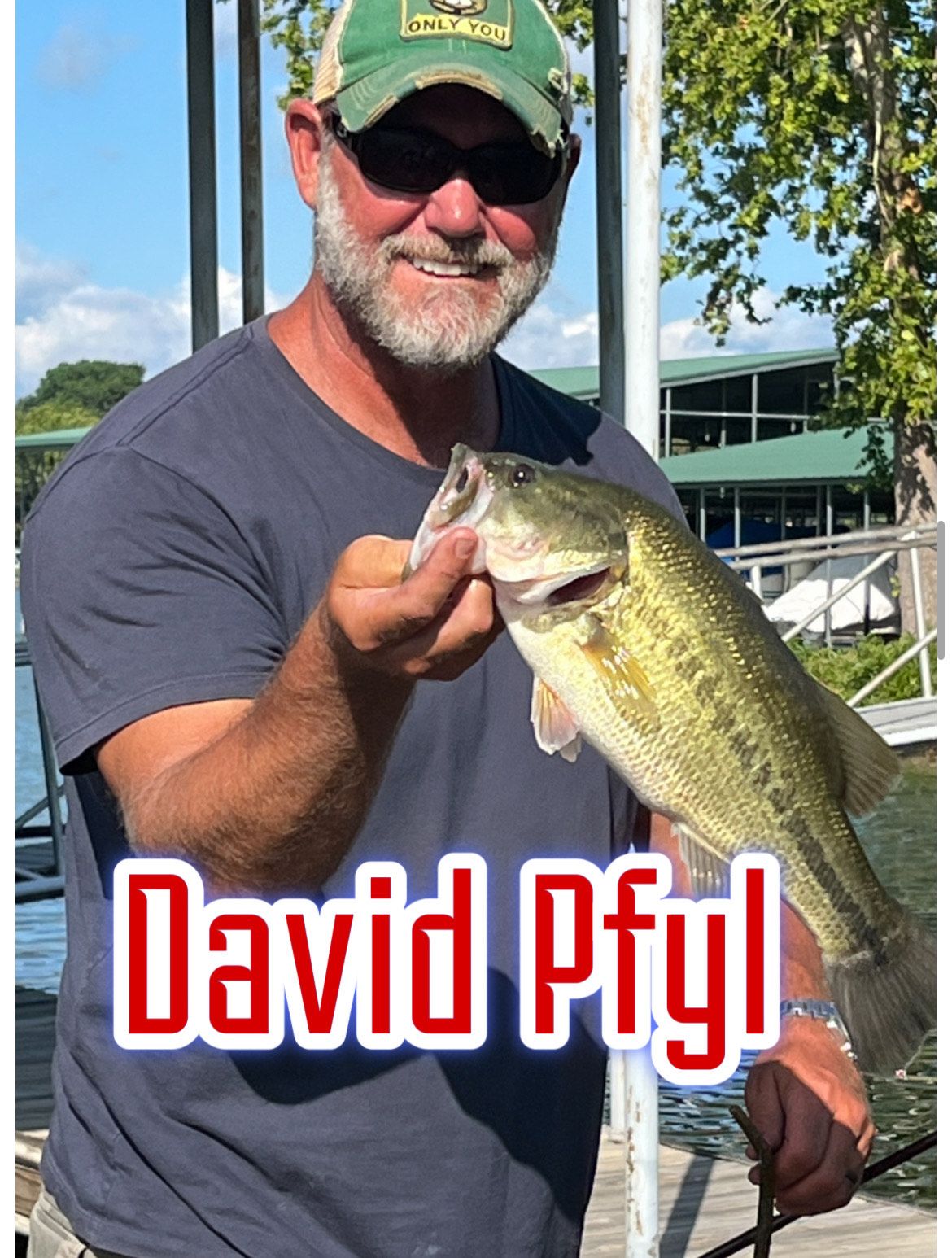 Man holding a largemouth bass outdoors, wearing a green cap and sunglasses, with “David Pfyl” text overlay.