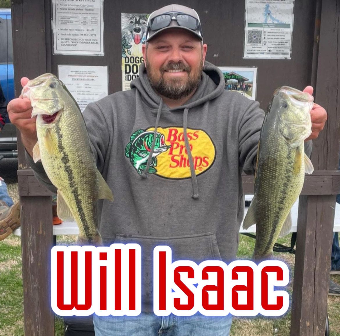 Man holding two large bass fish at a dock, with “Will Isaac” text at the bottom.