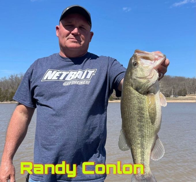 Man holding a large fish outdoors by a lake, with blue sky and yellow name text “Randy Conlon”