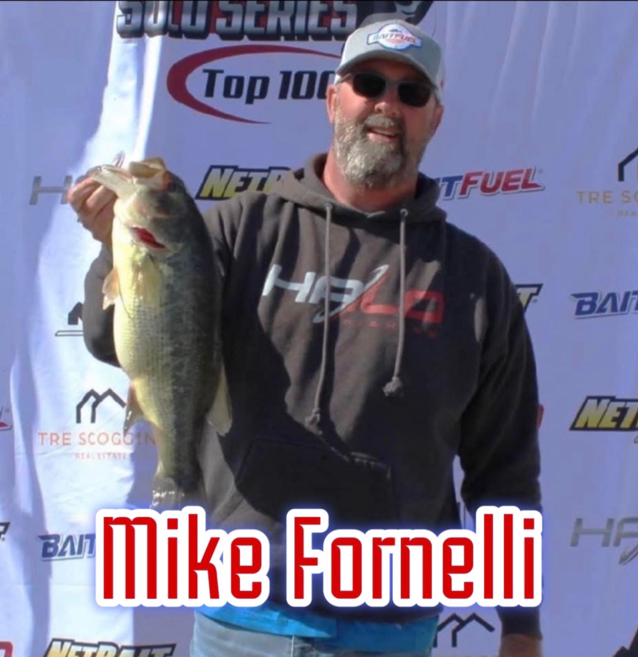 Man holding a large fish at a tournament backdrop with the name “Mike Fornelli” displayed