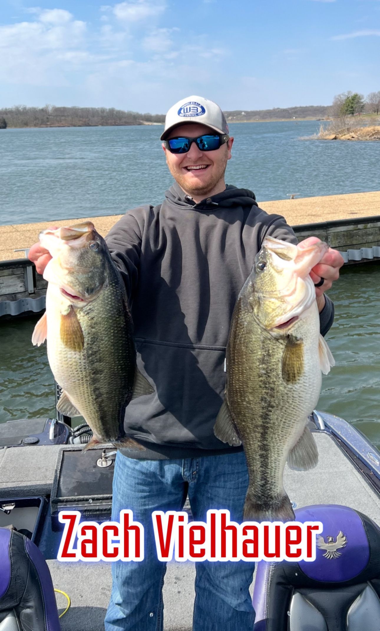 Man holding two large fish on a boat by a lake, with “Zach Viehauer” text at the bottom.