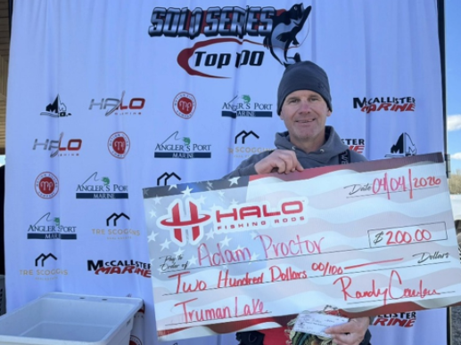 Man holding a large check at a snowy race event podium backdrop