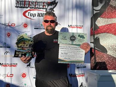 Man holding trophy and certificate at an awards podium backdrop outdoors