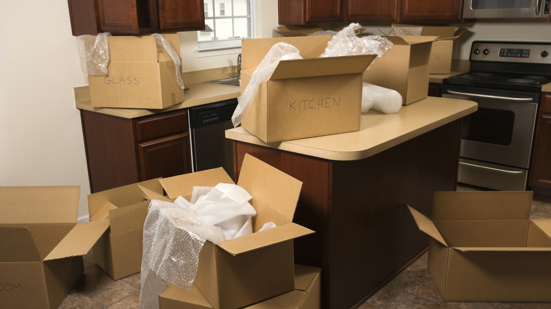 Cardboard boxes and packing materials scattered across a kitchen counter and floor