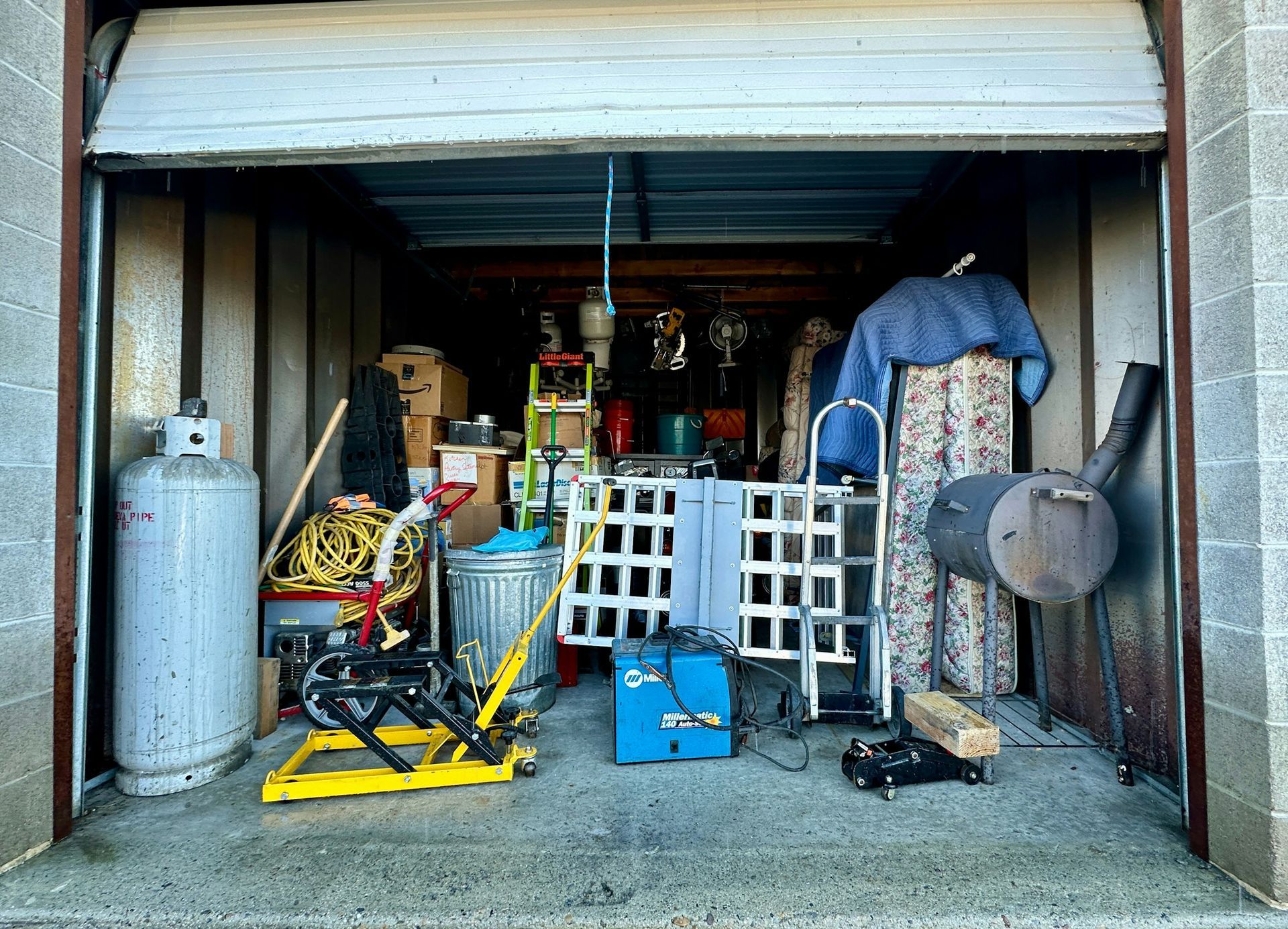 Garage packed with assorted tools, tanks, ladders, and equipment on shelves and the floor