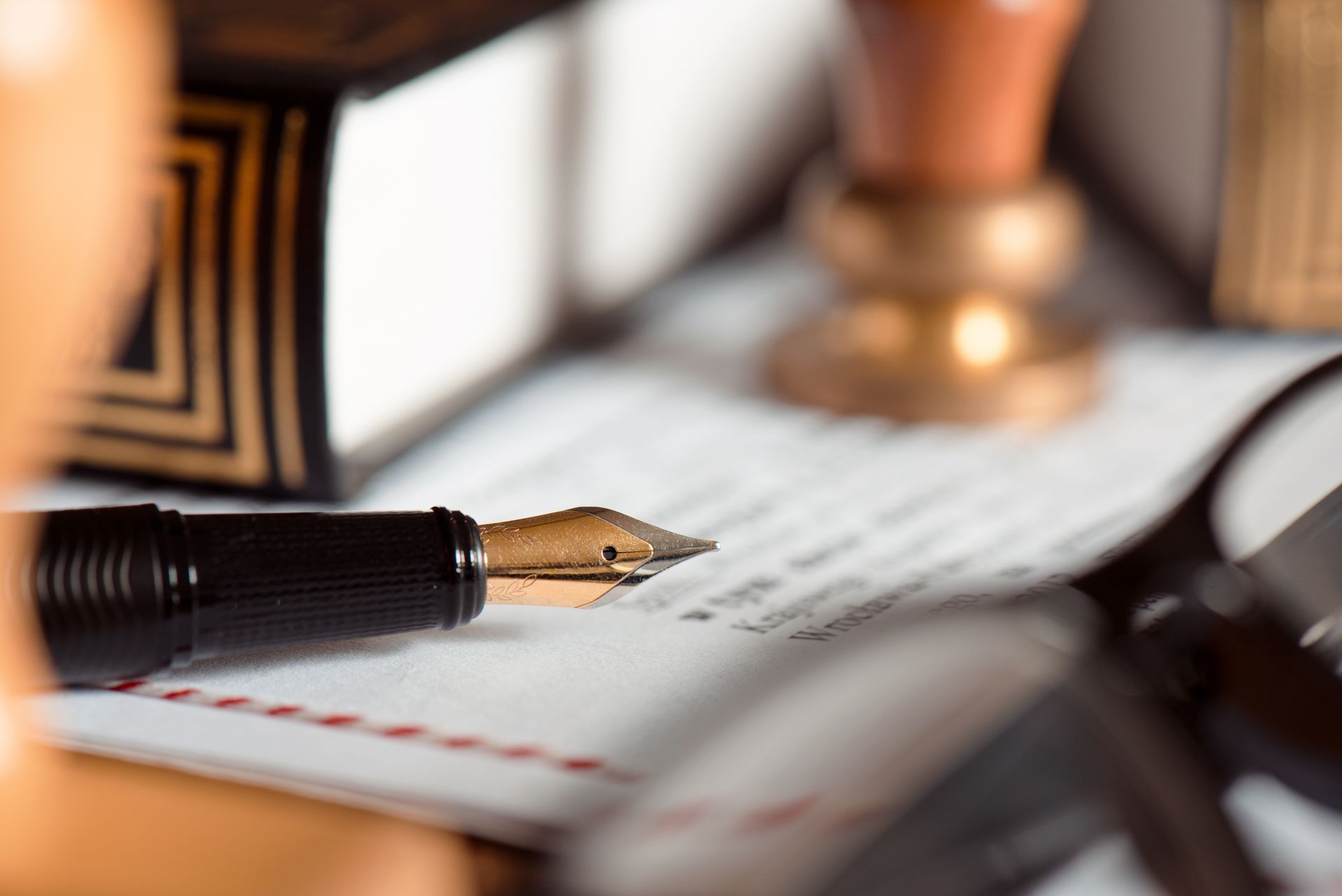 Fountain pen on legal document with notary stamp and book in background.