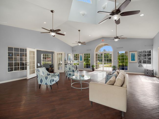Spacious room with seating, ceiling fans, and windows overlooking an outdoor area at The Point at Naples in Naples, FL.