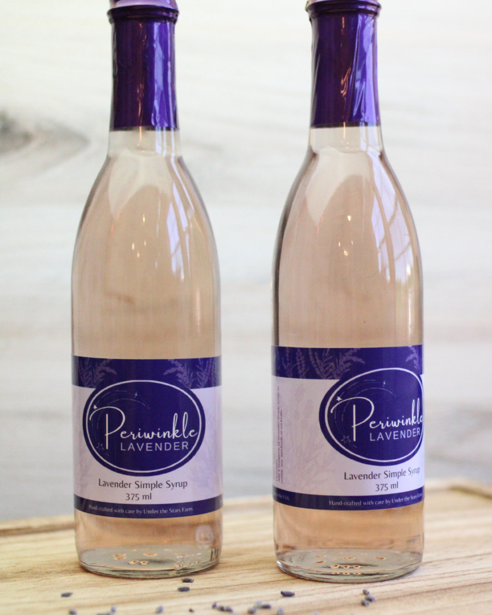 Two bottles of periwinkle lavender sitting on a wooden table