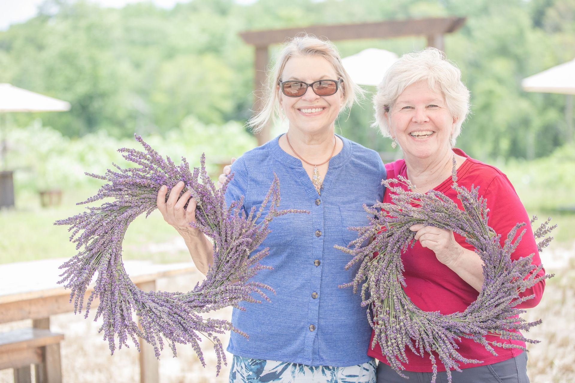 Two women are standing next to each other holding lavender wreaths.