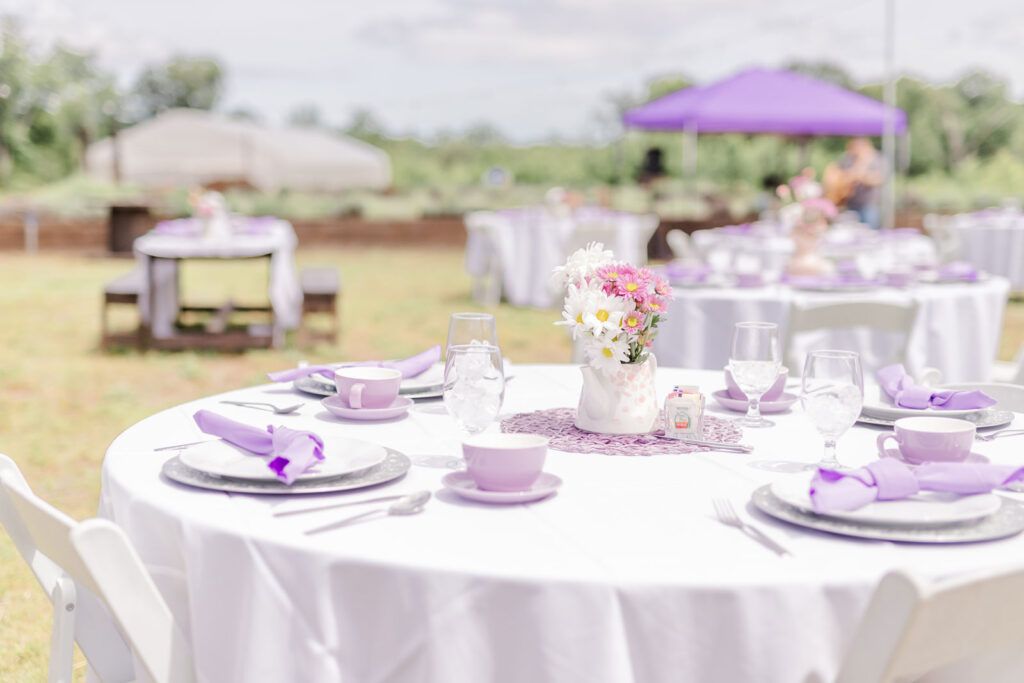 A table set for a tea party with purple napkins and plates.