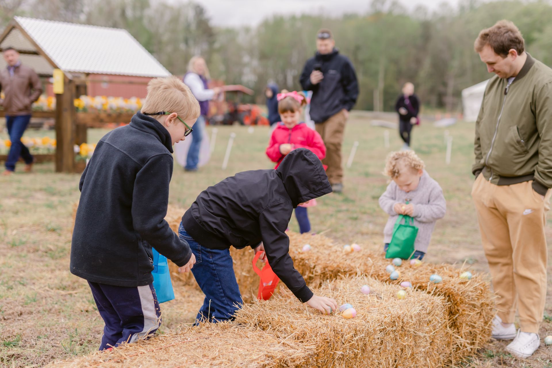 A group of children are playing with hay bales in a field.