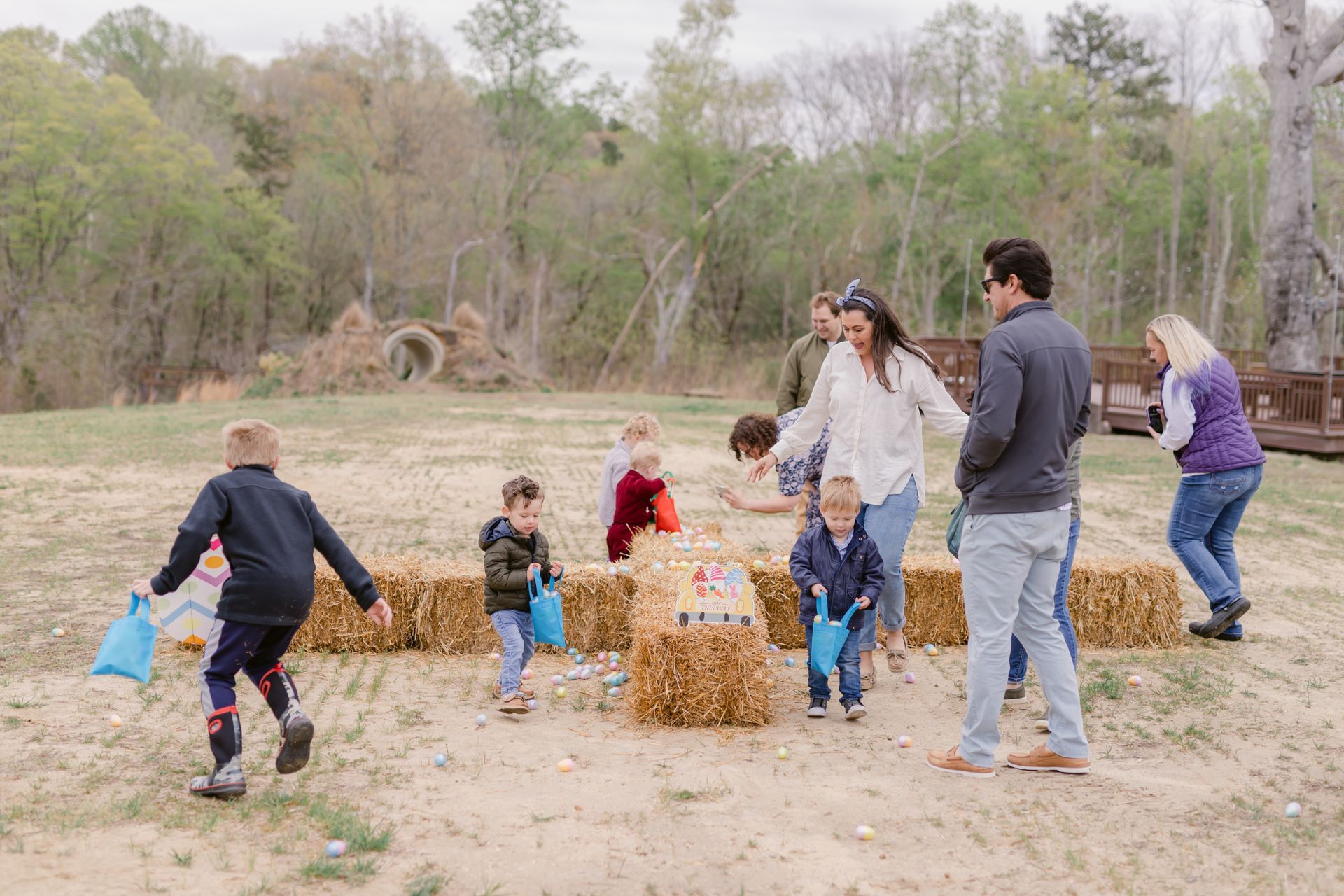 A group of people are standing around hay bales in a field.
