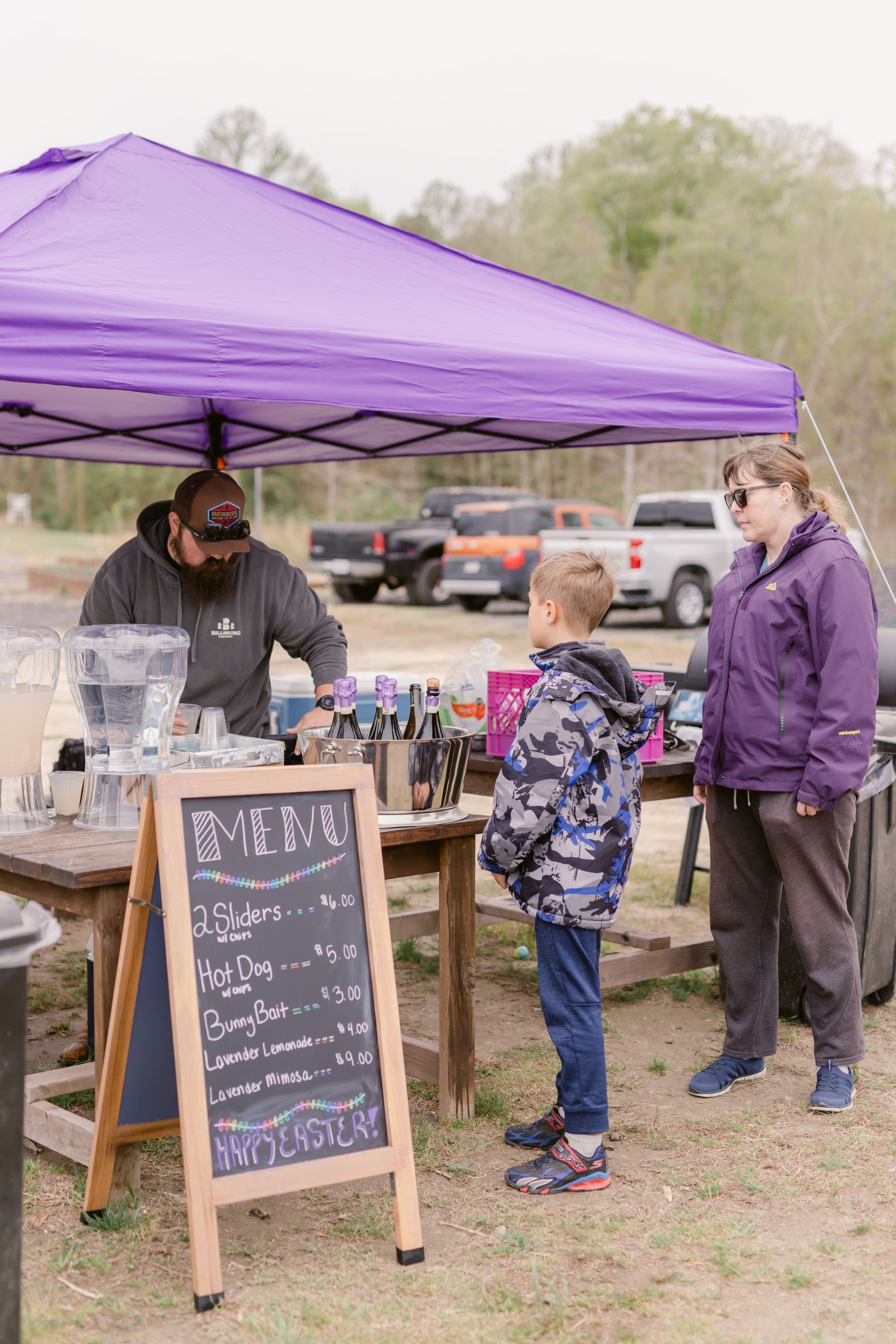 A man and a boy are standing under a purple tent.
