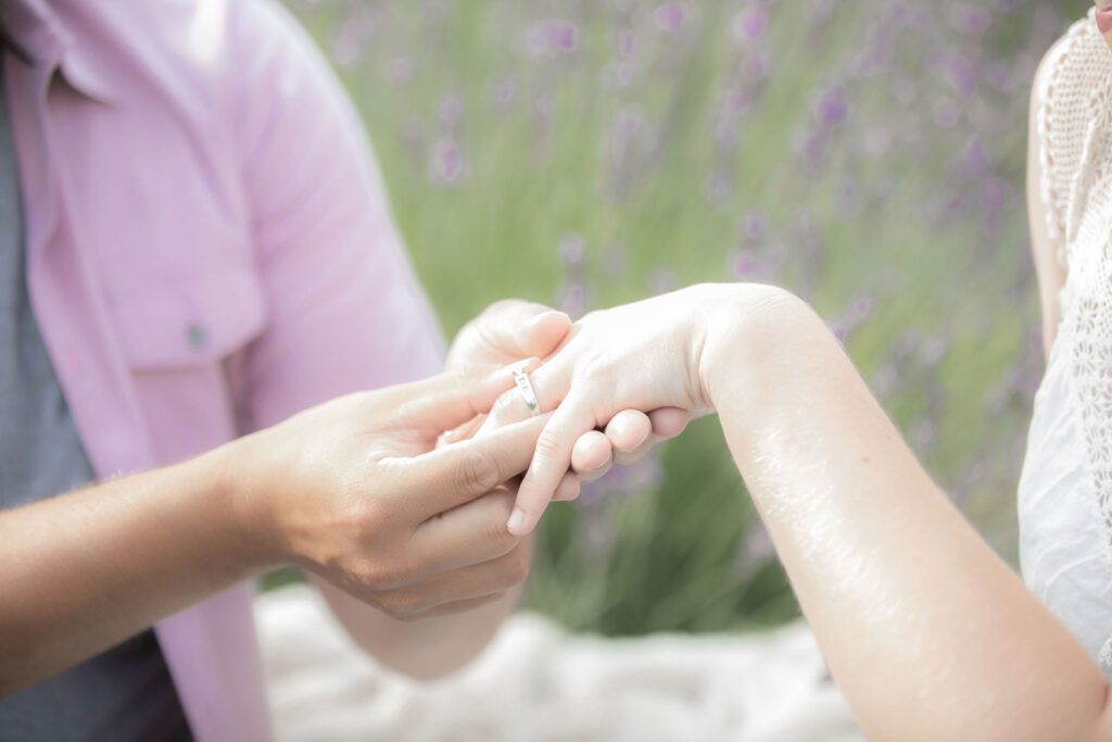 A man is putting a wedding ring on a woman 's finger.
