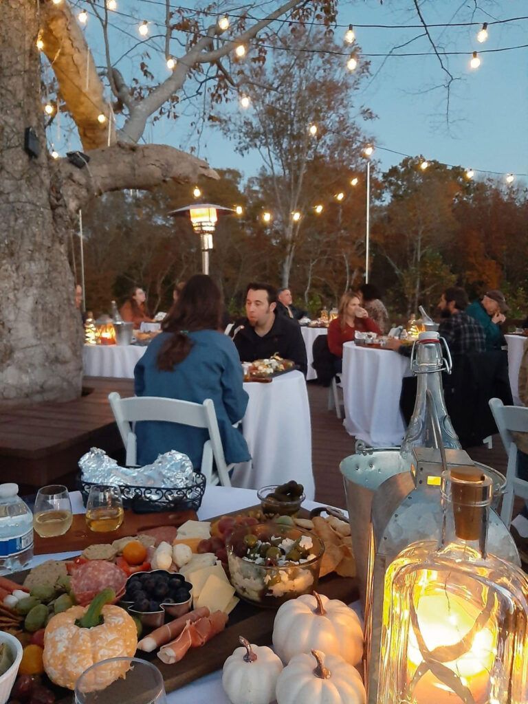 A group of people are sitting at tables outside eating food.