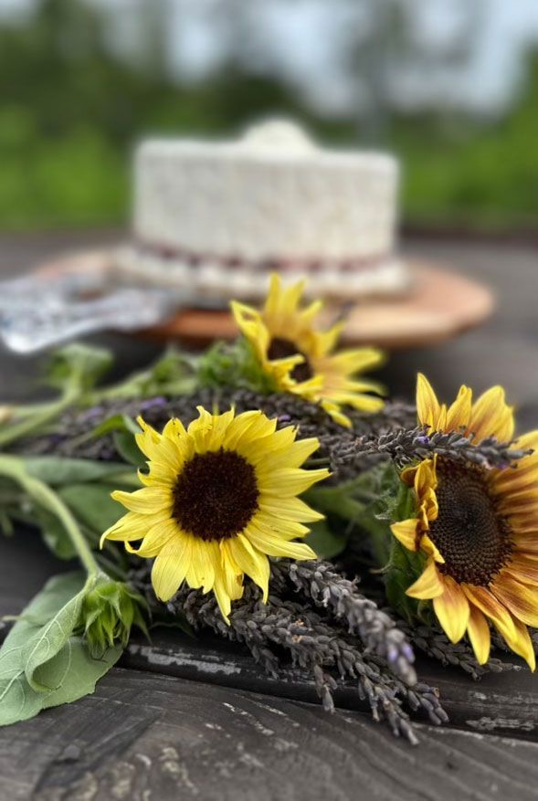 A bunch of sunflowers and lavender flowers on a wooden table.