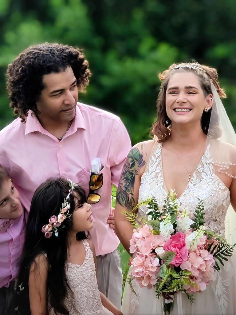 A bride and groom are posing for a picture with their children at their wedding.
