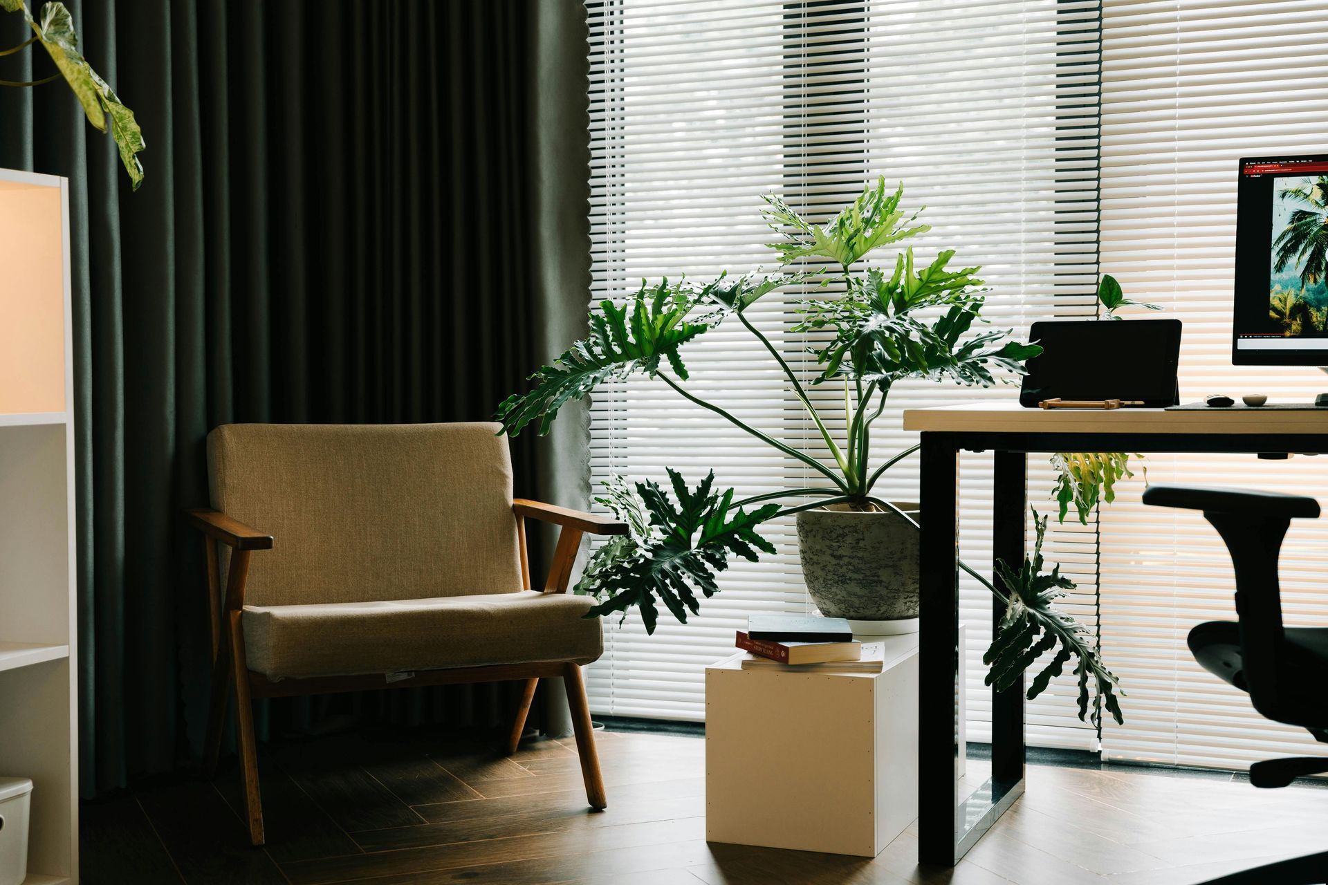 photo of a work space with a computer on a desk, a comfortable chair and some plants
