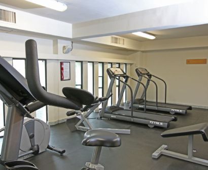 Gimnasio vacío con cintas de correr, bicicleta estática y bancos en una sala de entrenamiento luminosa.