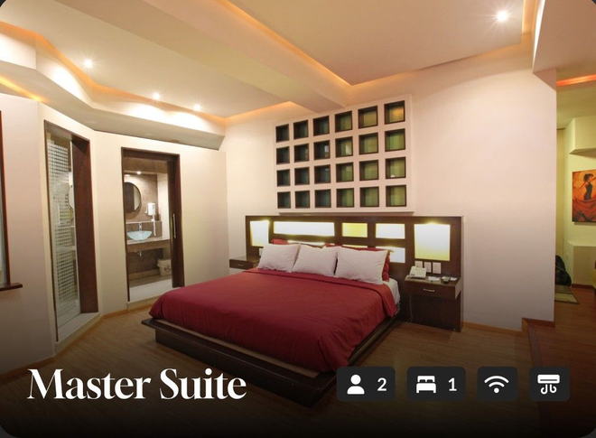 Suite principal con cama king size, iluminación cálida, obras de arte en las paredes e iconos de artículos de tocador.