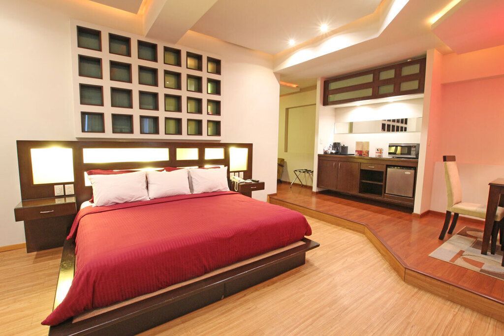 Habitación de hotel moderna con dos camas, iluminación cálida y un escritorio junto a la ventana.