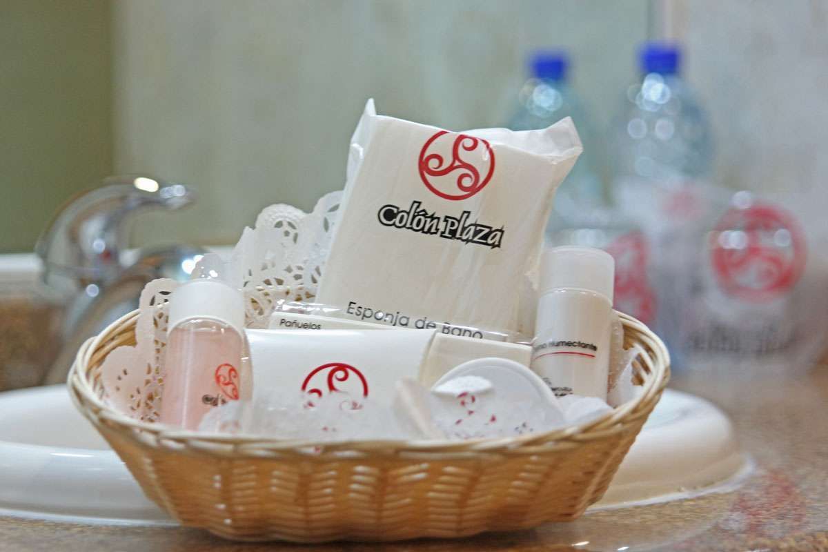 Cesta de productos de cuidado facial blancos con logotipos rojos sobre una mesa, con botellas y tarros difuminados al fondo.